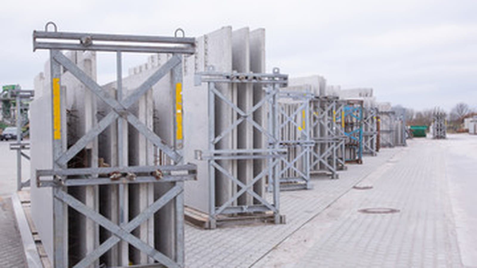 Precast wall panels held upright in steel transport frames in a plant yard