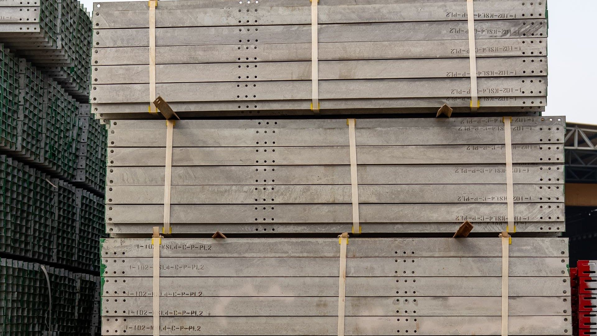 Banded stacks of precast concrete slabs marked with part codes in a plant yard